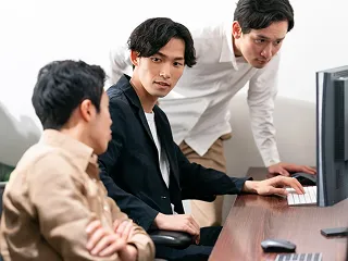 オフィスでパソコンを見ながら打ち合わせする社員