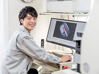 作業着を着てデスクでCAD画面を確認する社員